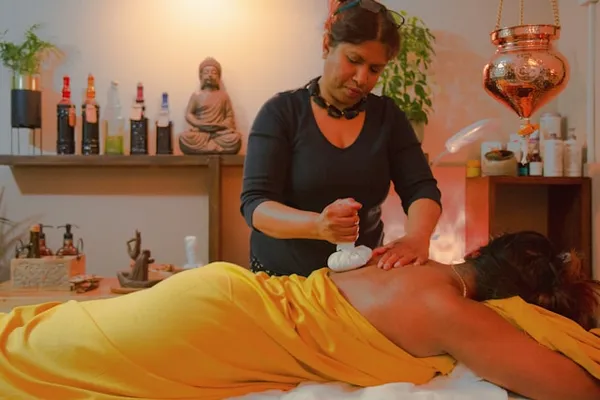 Therapeutin mit Kräuterstempel bei ayurvedischer Rückenbehandlung
